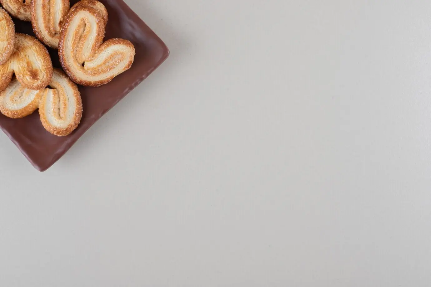 Ein Bündel blättriger Kekse auf einer Platte vor weißem Hintergrund.